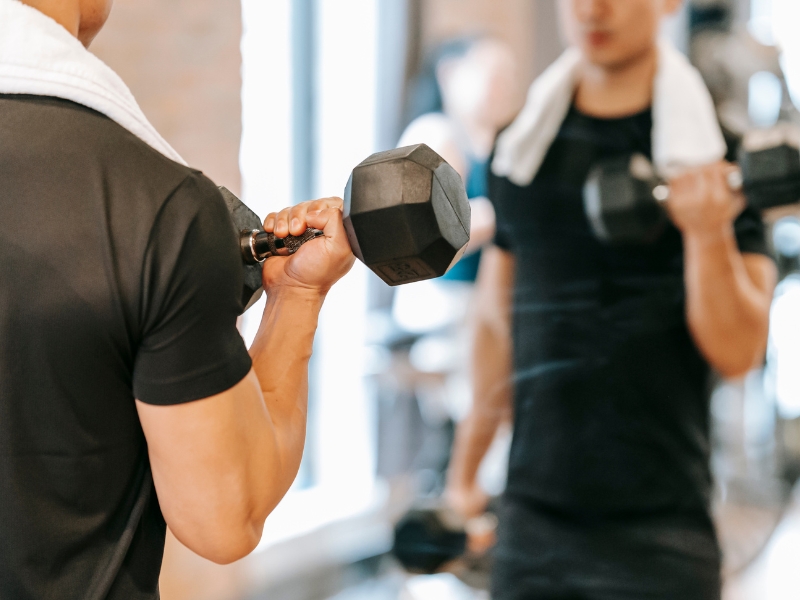 man using gym weights in front of mirrow