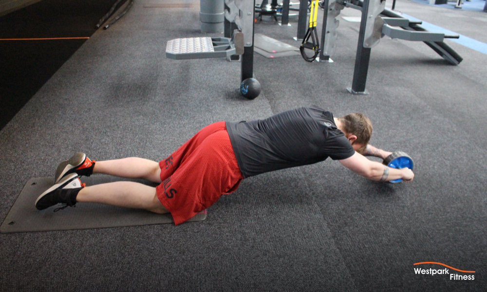ab wheel exercise at westpark fitness image of male personal trainer on gym floor using ab wheel