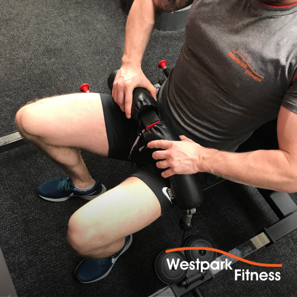 booty builder machine at westpark fitness male gym goer sitting in seat of machine fastening seatbelt around his waist