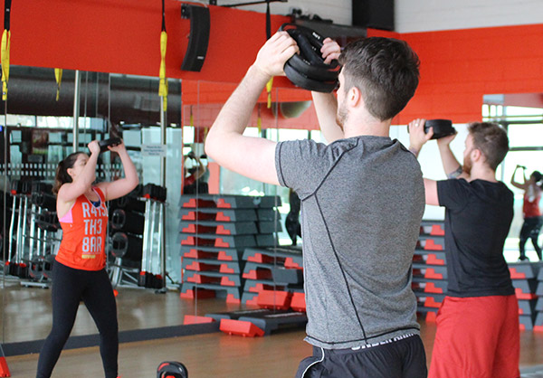 beach body guide westpark fitness two male members wathcing female instructor showcase exercises