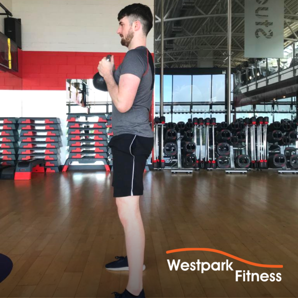 male gym goer standing up straight and holding a kettlebell to complete the goblet squat exercise at westpark fitness