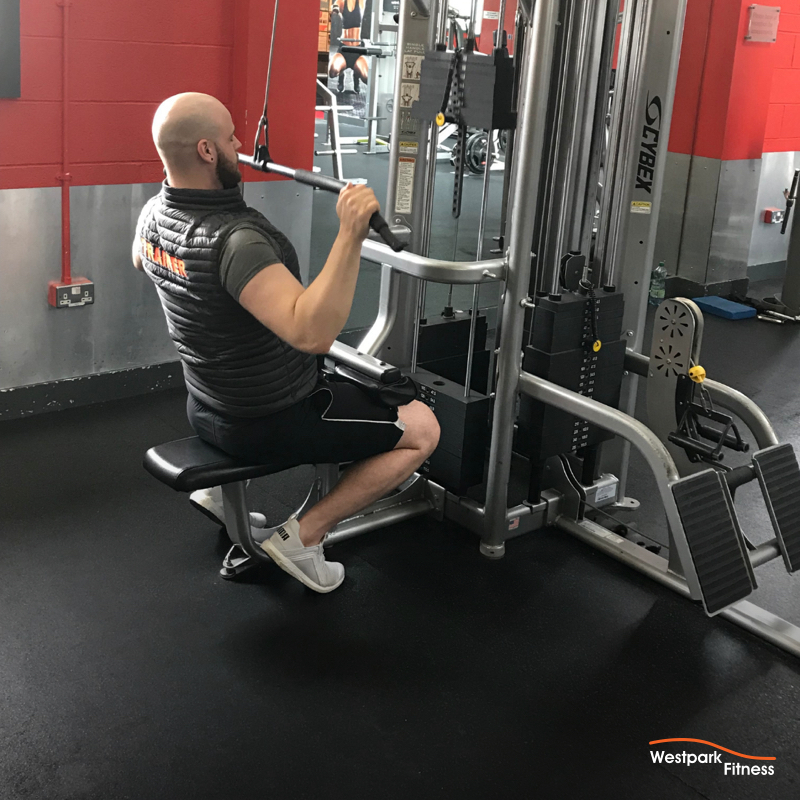 lat pulldown male gym goer sitting on the lat pulldown machine in westpark fitness with the handlebar down at his chest