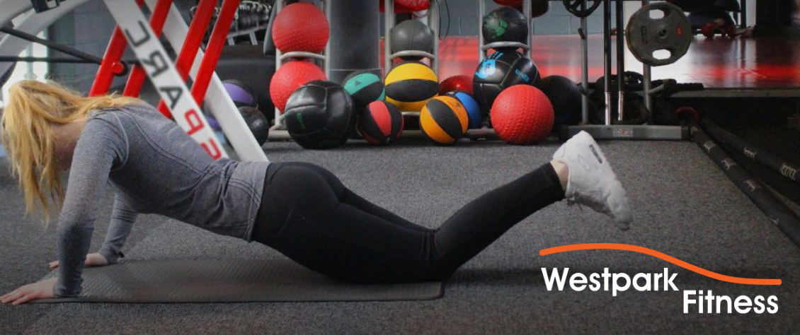 plank exercise at westpark fitness female gym goer in plank position on the ground with knees bent and legs raised