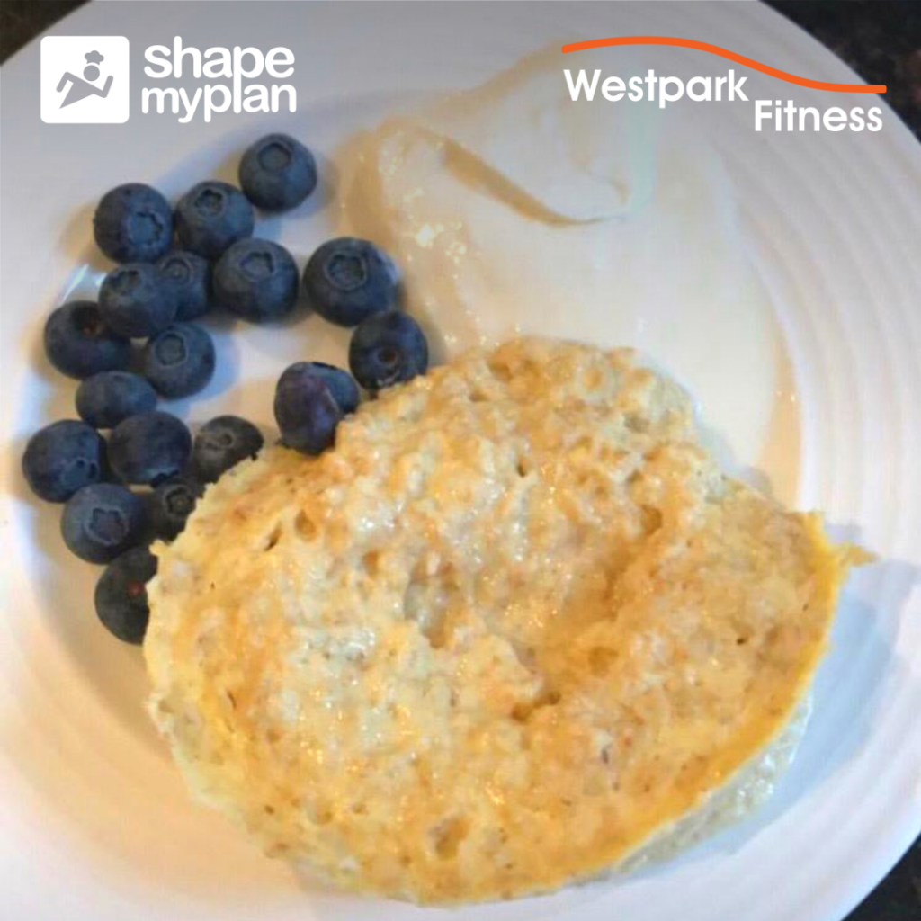 porridge in a cup white plate with porridge and yoghurt and blueberries on it