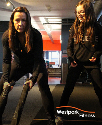 battle ropes westpark fitness trainer showing a child how to use them on the gym floor